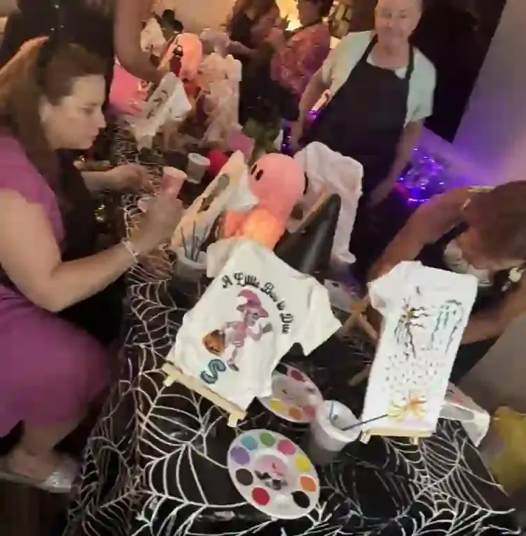Engage in Creativity: A Lively Craft Table Scene with Spider Web Tablecloths and Vibrant T-Shirt Painting
Capture the essence of creativity at a bustling craft table, adorned with festive spider web tablecloths perfect for Halloween or themed events. In the foreground, a woman skillfully wields a paintbrush, bringing designs to life on an array of colorful T-shirts. Her focus is matched by several others who gather around, each contributing to the artistic atmosphere. Paint palettes and cups speckle the scene, enhancing the vibrant palette of this interactive experience. Decorative lighting in the background casts a warm glow over this lively setting, ideal for those seeking unique activities from Ultimate Baby Shower Rentals. This picture-perfect moment reflects not only collaborative spirit but also showcases innovative T-shirt designs that add flair to any gathering.
