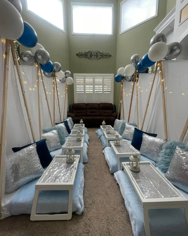 A previous Slumberr setup with white teepees, blue and silver pillows and balloon toppers.