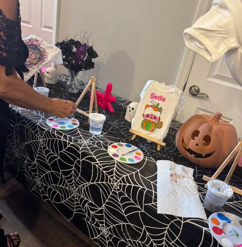 Slumberr Halloween painting table with pumpkin art, ghost ceramics and a spiderweb tablecloth.
