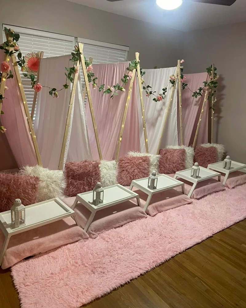 A previous Slumberr sleepover with white teepees, pink cushions, florals and tray tables.