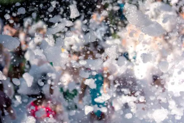 People enjoying a foam-filled teepee party event, with numerous bubbles obscuring parts of the view.