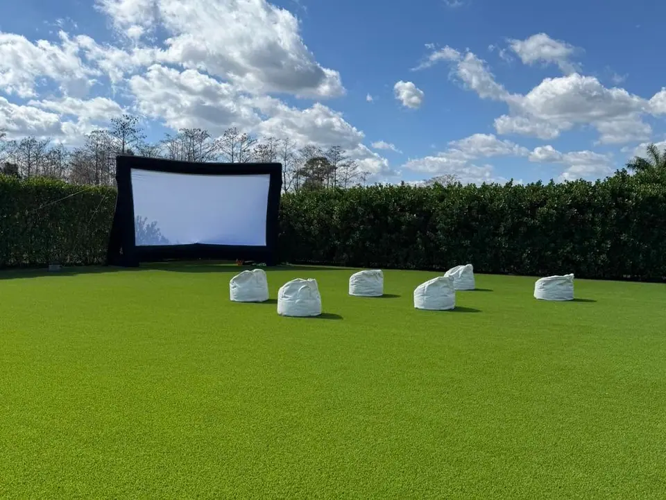 Outdoor movie night: inflatable screen and white loungers on a wide lawn