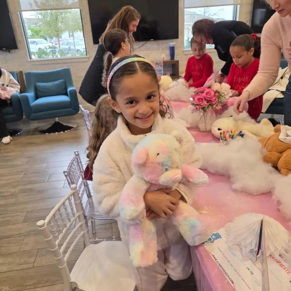 Girl holding her new stuffed bear at a build-a-bear party
