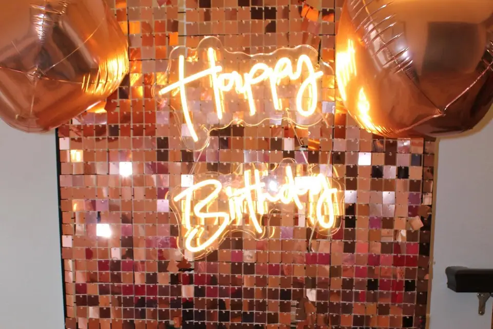 Rose-gold sequin wall with a Happy Birthday neon sign