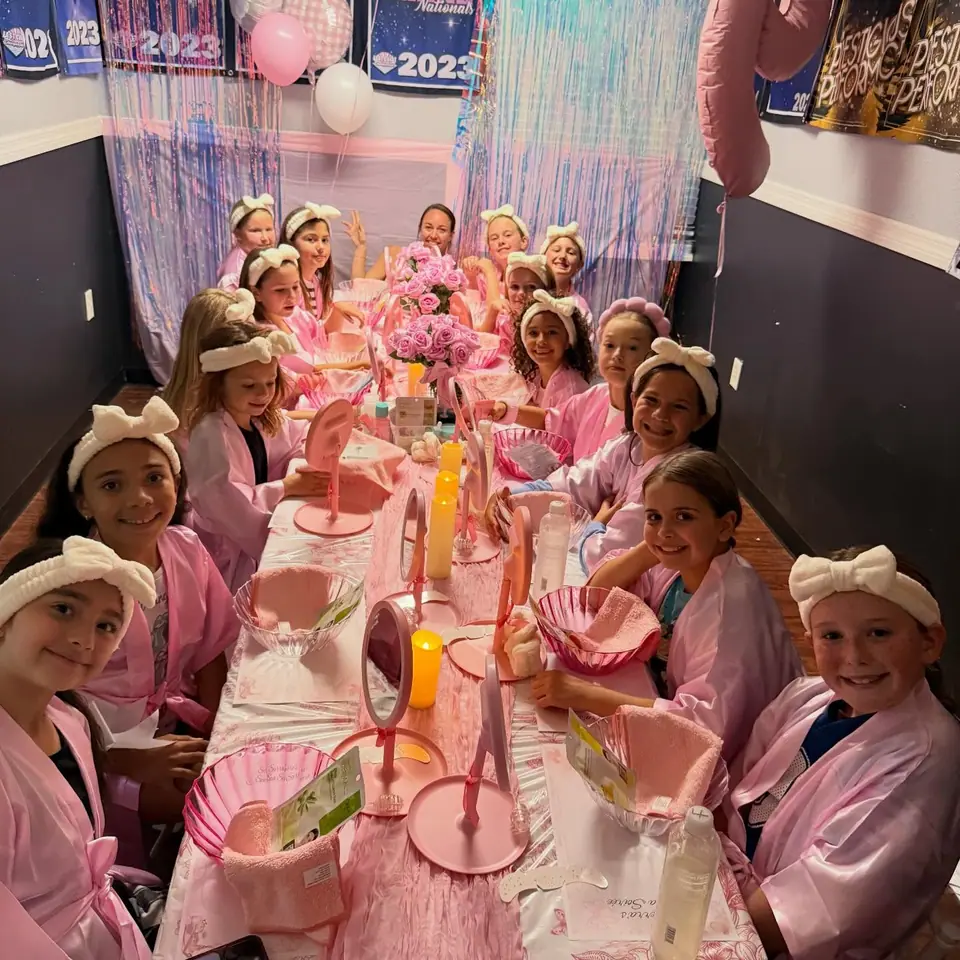 Girls in pink robes and headbands at a Slumberr spa party table