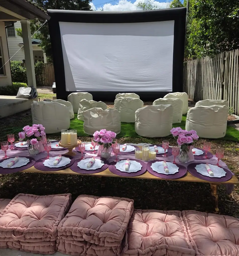 Luxury picnic table with pink cushions in front of an outdoor movie screen