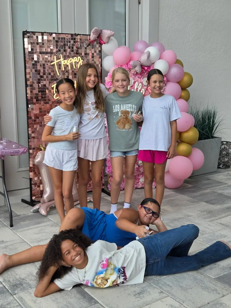 Girls posing at a pink birthday backdrop at a Slumberr party