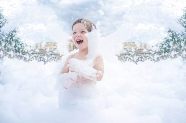 A child is joyfully playing in an outdoor area filled with foam, reminiscent of a fun slime party, surrounded by a frothy, cloud-like environment under a partly cloudy sky.