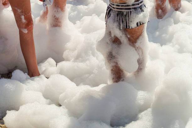People stand in thick foam, with their legs partially covered by it, at a lively kids party rental.