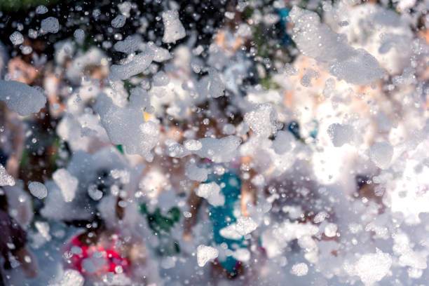 People enjoying a foam-filled teepee party event, with numerous bubbles obscuring parts of the view.