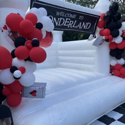 Inflatable entrance with "welcome to Wonderland Wonders" banner, adorned with black, white, and red balloons and playing card decorations.