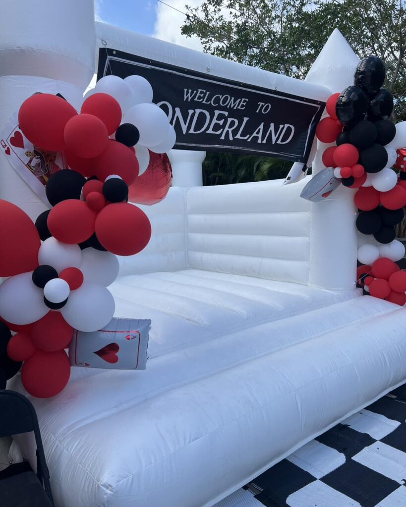 Inflatable entrance arch decorated with red, white, and black balloons and a sign reading "Welcome to the 2024 Ultimate Sleepover" above a checkered floor.