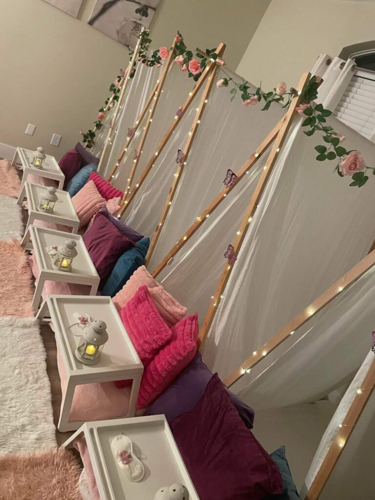Indoor seating area with rows of benches adorned with pink cushions and draped with fairy lights and floral decor, perfect for the 2024 Ultimate Sleepover.