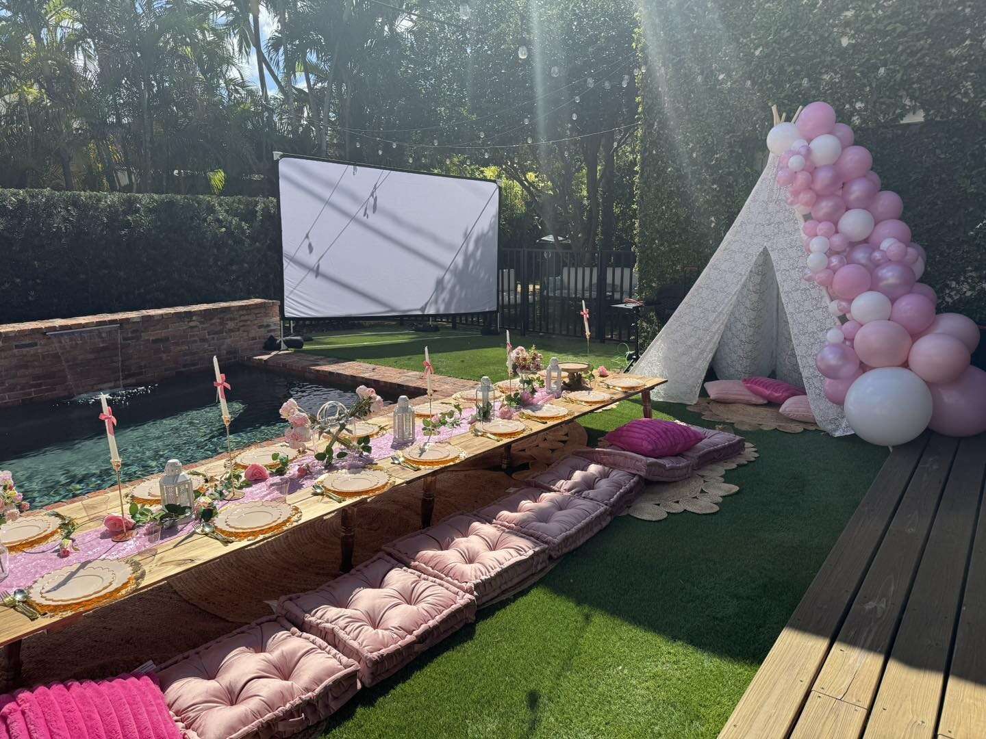 Poolside outdoor movie night with inflatable screen and teepee lounge